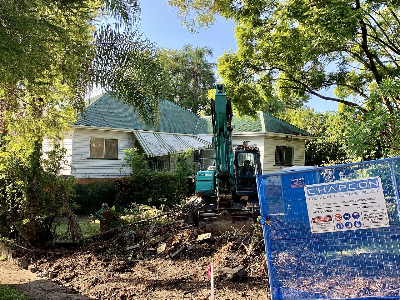 An excavator knocking down a weatherboard house